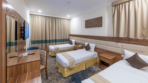 A hotel room with two beds, a desk, a TV, and a bathroom. - Joury Al Hada Hotel (Makkah)