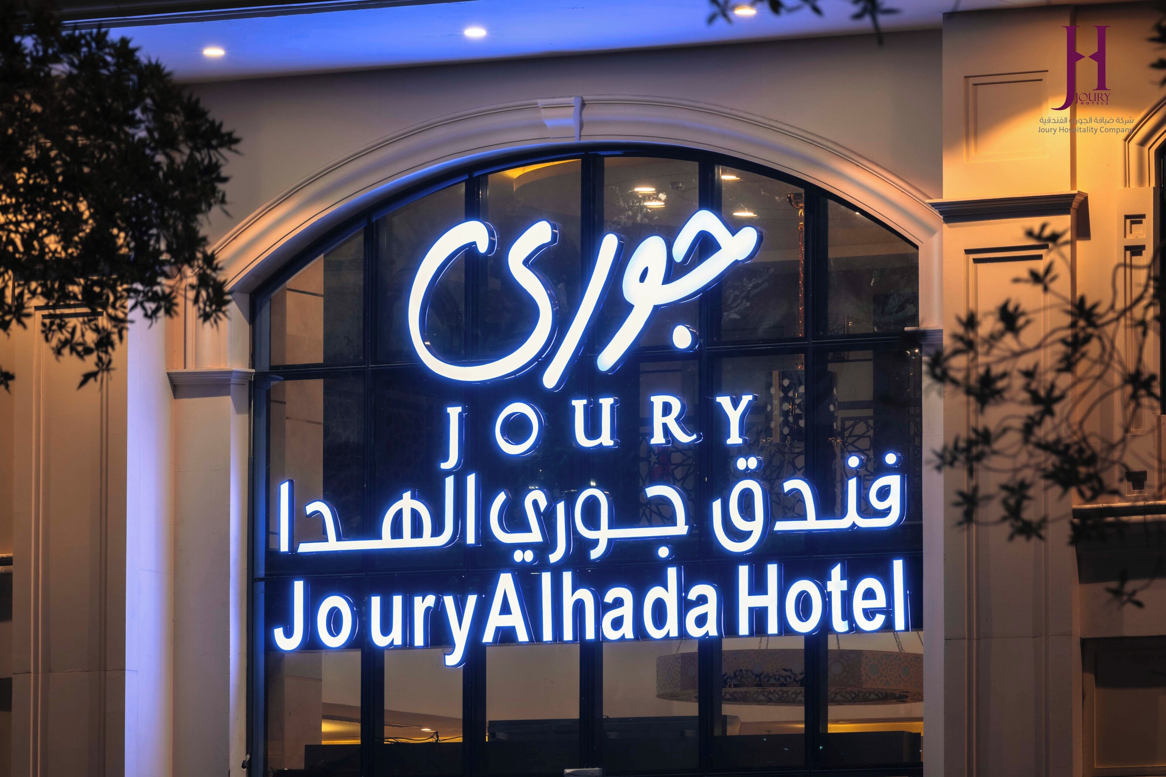 Un letrero de hotel con el nombre 'Joury Alhada Hotel' en varios idiomas.