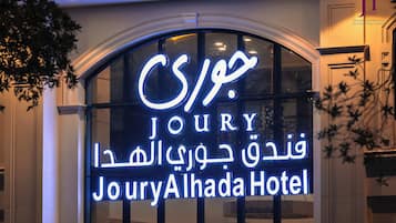 Un letrero de hotel con el nombre 'Joury Alhada Hotel' en varios idiomas.