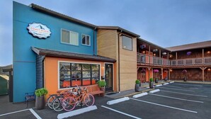 A building with a blue and orange facade, a sign reading 'Coast River Inn,' and a parking lot with bicycles.