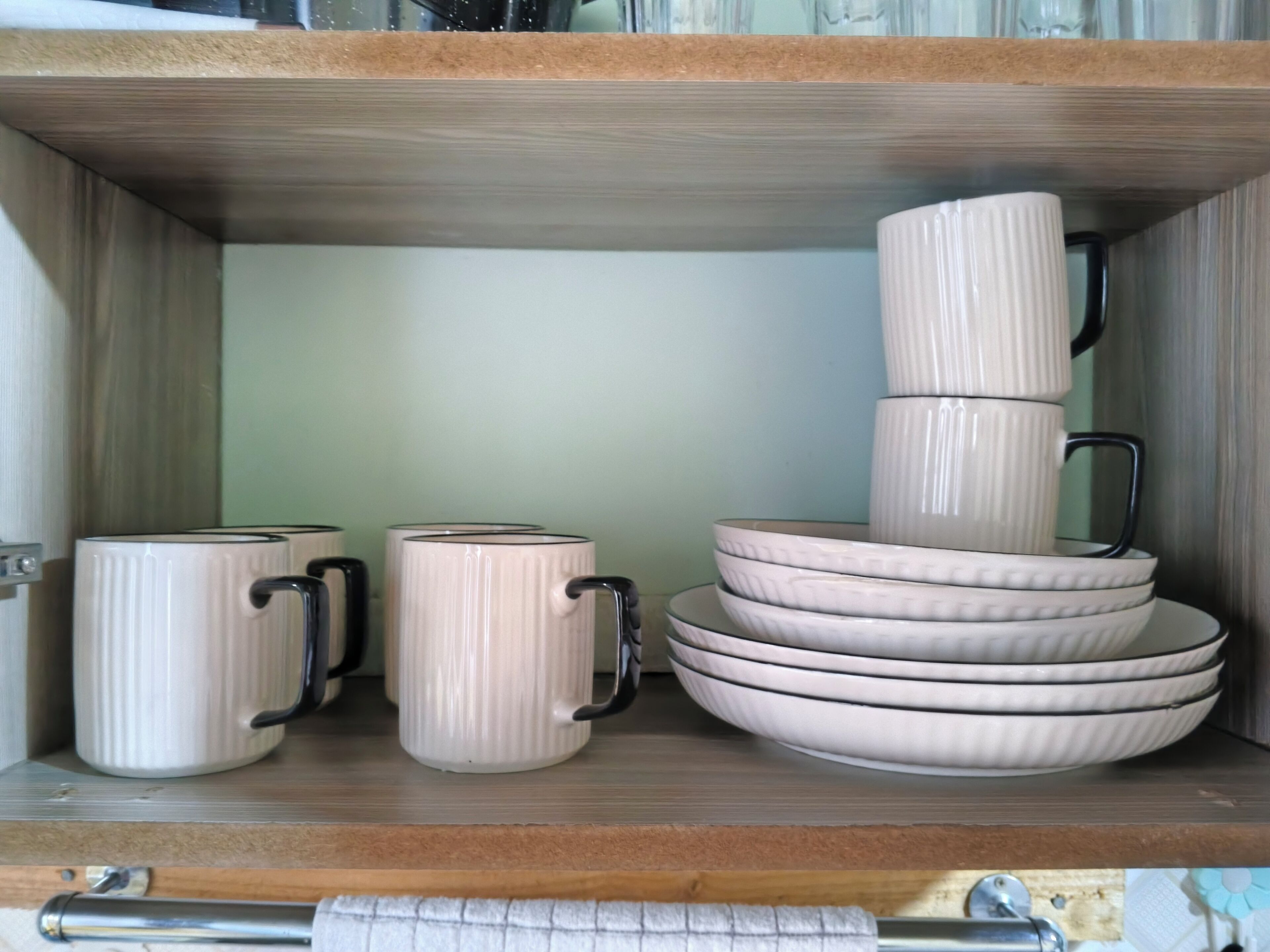 Una estantería con tazas y cuencos de cerámica apilados.