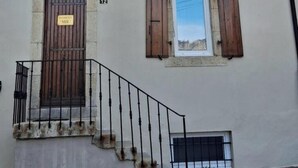 A building with multiple windows, a door with a sign, and a staircase leading to the entrance.