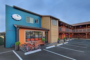 Rakennuksessa on sininen ja oranssi julkisivu, ja sen yläpuolella on kyltti, jossa lukee ”Coast River Inn”. Lisäksi rakennuksen edessä on pysäköintialue, jossa on pyöriä.