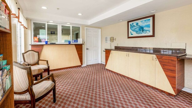 Un vestíbulo de hotel con un mostrador de recepción, un cuadro enmarcado en la pared y una alfombra estampada.