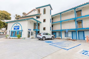 A two-story motel with a blue and white color scheme, a parking lot, and a handicap-accessible parking space.