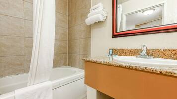 Ein Badezimmer mit Badewanne, Waschbecken, Spiegel und Handtuchhalter.