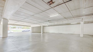 An empty parking garage with concrete floors and walls, and a few cars parked outside. - 2 Queen Bed | Smoking (San Clemente, CA)