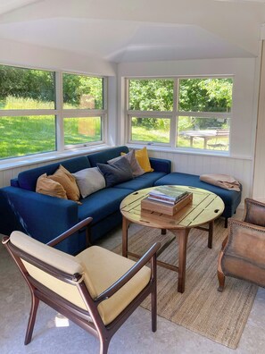 A room with a blue sofa, a round wooden coffee table, and two chairs with woven seats.