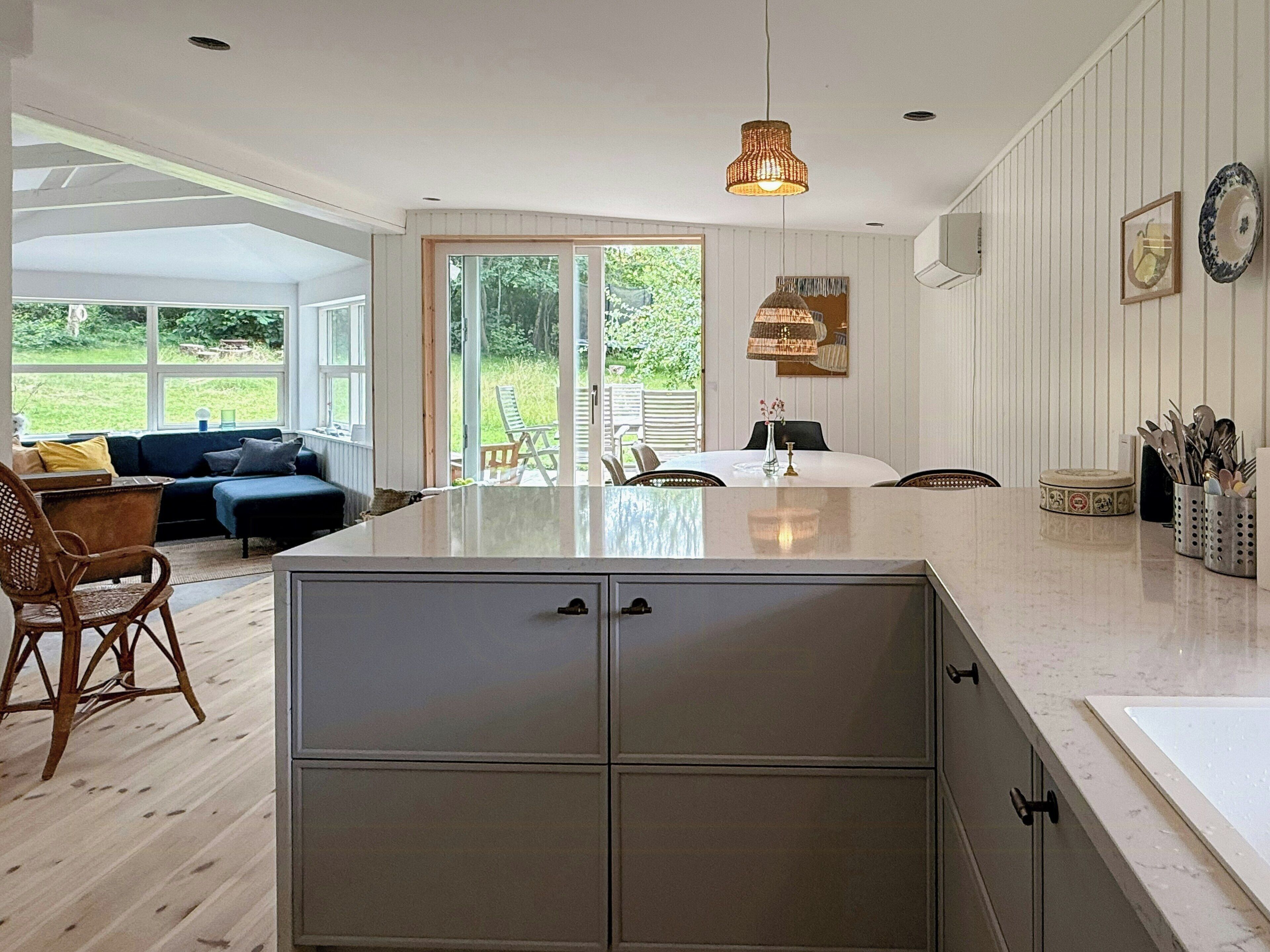 A modern kitchen with a central island, dining area with chairs, and a view of the outdoors.