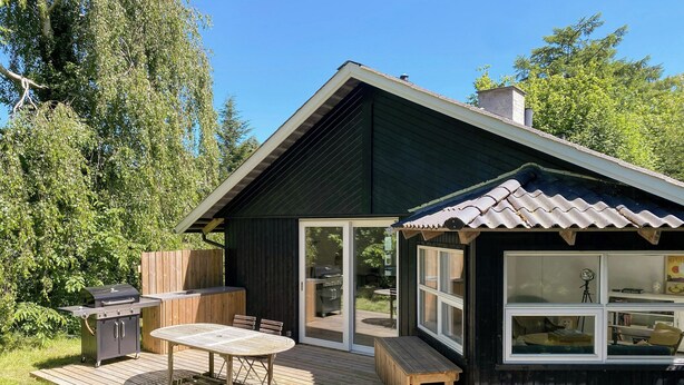En träaltan med en grill, ett bord och stolar.