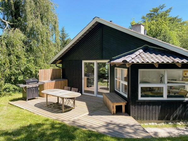 A wooden deck with a grill, a table, and chairs.