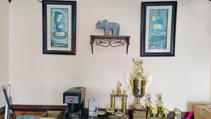 Una cocina con cafetera, trofeos y obras de arte enmarcadas en la pared.