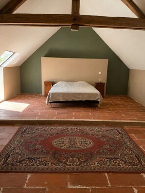 A room with a sloped ceiling, a bed with a headboard, two bedside tables, a patterned rug, and a skylight. - A charming farmhouse between Beauval and Les Châteaux (Selles-sur-Cher)