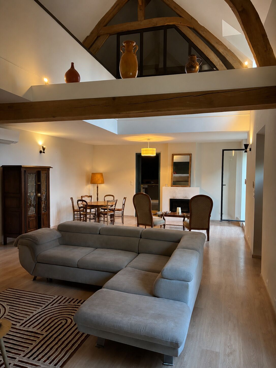 A spacious living area with a large sectional sofa, a dining table with chairs, and a fireplace.