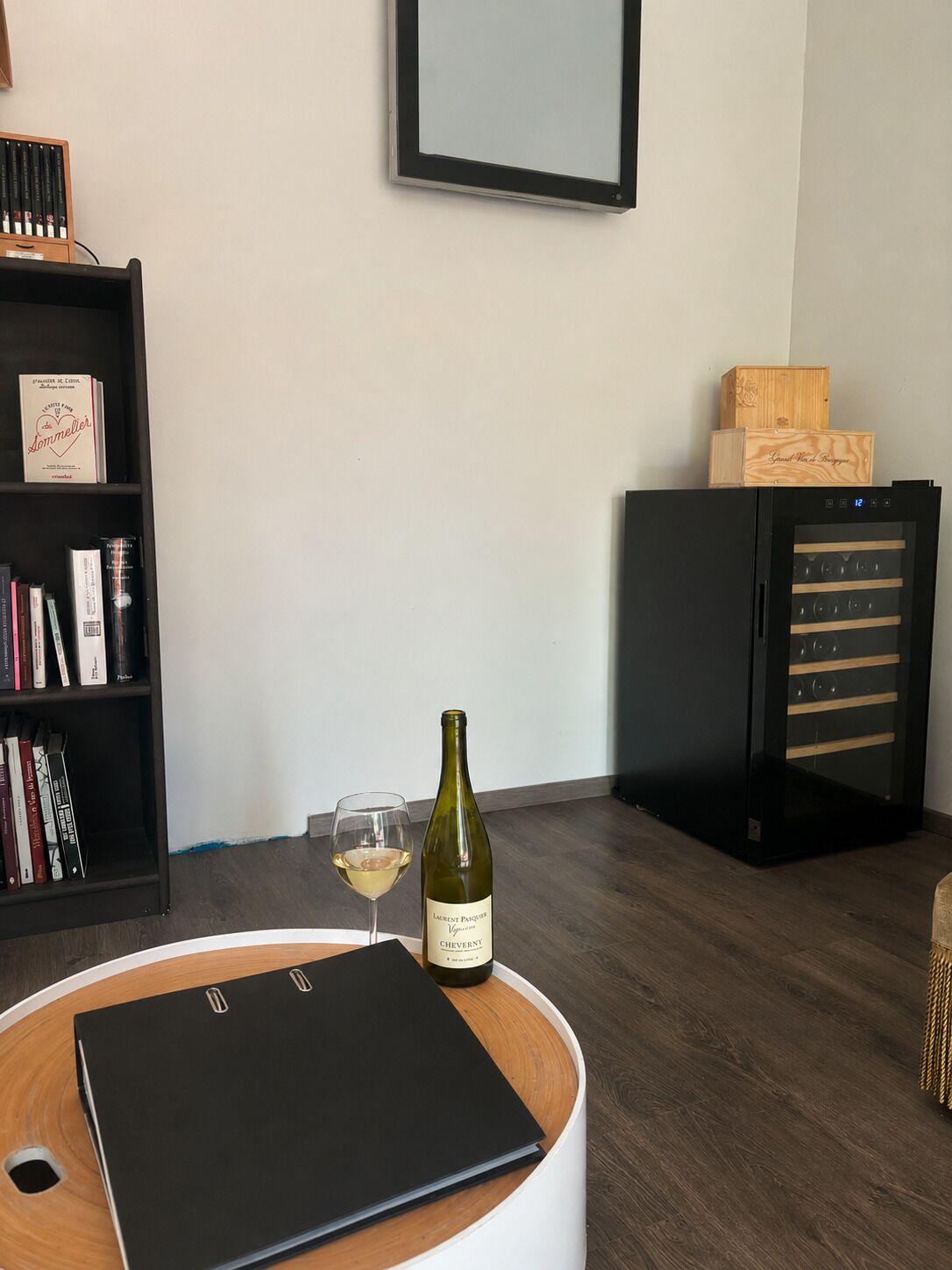 Ein Zimmer mit Bücherregal, Weinflasche und einem Weinglas auf einem Tisch.