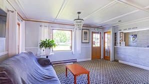 A hotel lobby with a patterned carpet, a sofa, a table, a chandelier, and a reception desk.