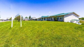 A building with a green roof, a grassy lawn, and a clear blue sky.
