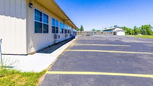 A building with a parking lot, large windows, and a clear sky.