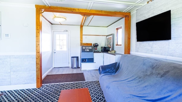 A compact living space with a kitchenette, a sofa, and a television mounted on the wall.