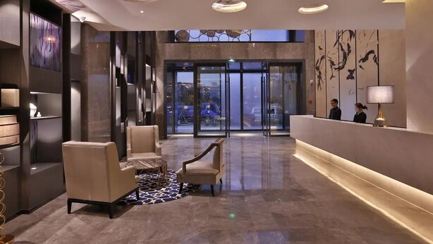 A hotel lobby with a reception desk, seating area, and a view through the glass doors. - Crystal Orange Hotel Hangzhou Qianjiang New City Jinjiang (Hangzhou)