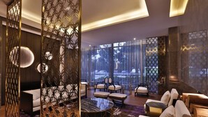 A modern hotel lobby with a seating area, a round table, and a decorative partition. - Crystal Orange Hotel Hangzhou Qianjiang New City Jinjiang (Hangzhou)