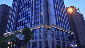 A high-rise building with a modern architectural design, featuring a prominent corner entrance and multiple floors. - Crystal Orange Hotel Hangzhou Qianjiang New City Jinjiang (Hangzhou)