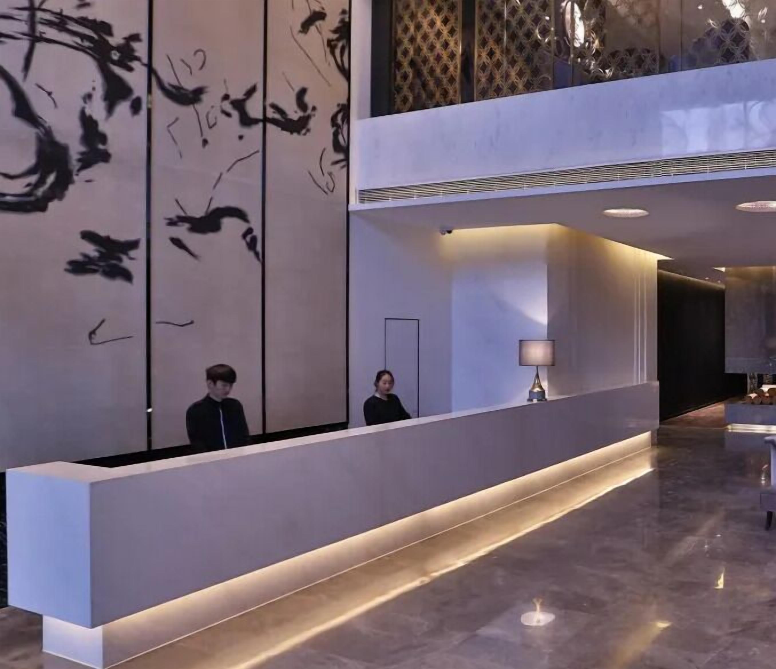 Una reception dal design moderno, con una persona dietro e un grande quadro astratto appeso al muro.