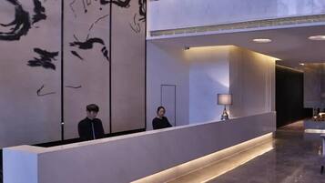 Una reception dal design moderno, con una persona dietro e un grande quadro astratto appeso al muro.