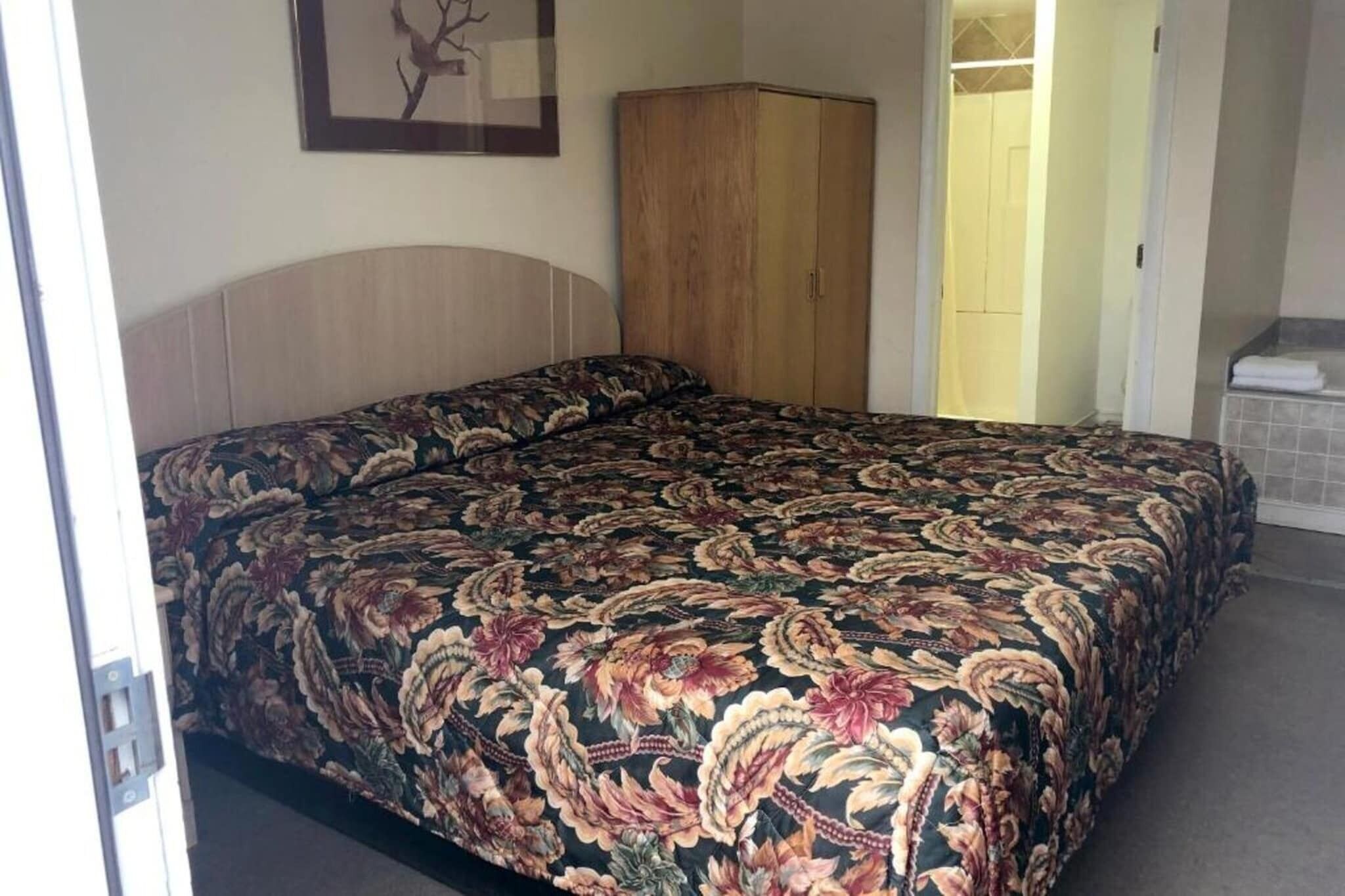 A bedroom with a bed, a wardrobe, and a door leading to a bathroom.