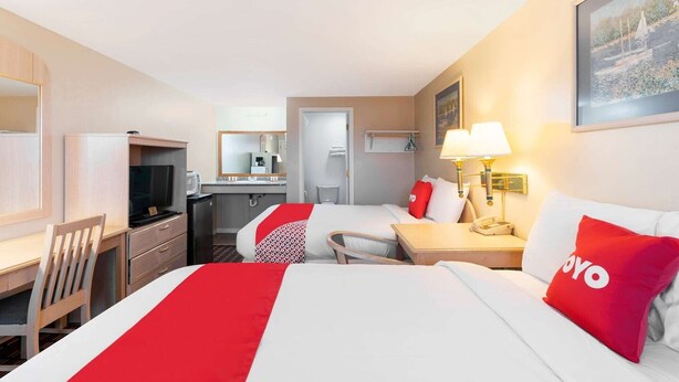 Ein Hotelzimmer mit Bett, Schreibtisch, Stuhl, Fernseher und einer kleinen Küche.