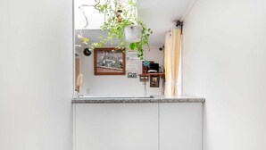 Eine Küche mit Granit Arbeitsplatte, hängenden Pflanzen, einem gerahmten Bild und einem kleinen Regal mit Gegenständen.