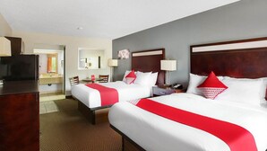 Ein Hotelzimmer mit zwei Betten, einem Schreibtisch, einem Fernseher und einem durchgegangenen Badezimmer.