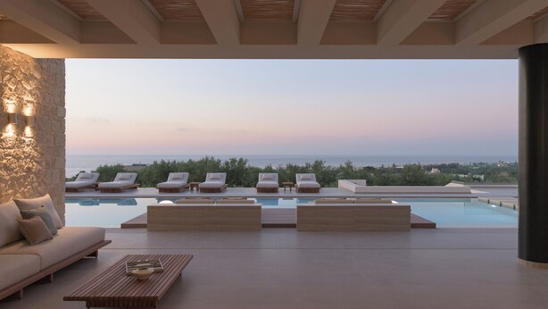 Eine moderne Lounge im Freien mit Pool, Sitzgelegenheiten und Blick auf das Meer.