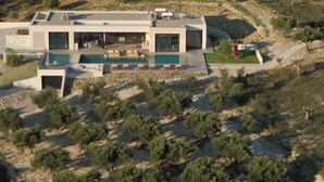 Ein modernes Haus mit Swimmingpool, Sitzgelegenheit im Freien und Blick auf die umliegende Landschaft.