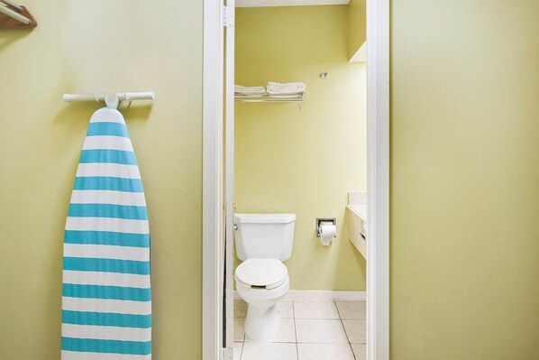 Een badkamer met een toilet, een handdoekhouder met opgevouwen handdoeken, en een gestreepte handdoek aan een rek.