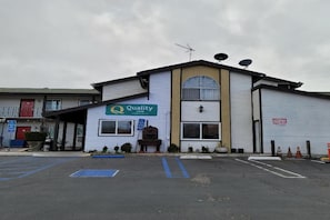 Een gebouw met een 'Quality Inn'-bord, een parkeerplaats en een hekpoort.