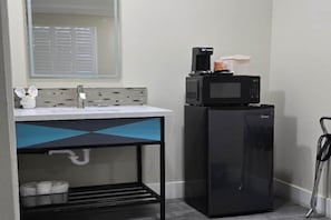 Een kleine keuken met een magnetron, koffiezetapparaat en een kleine koelkast.