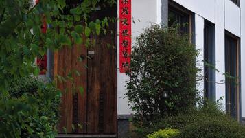 A building entrance with a wooden door, a red vertical sign with Chinese characters, and a staircase leading up to the door.