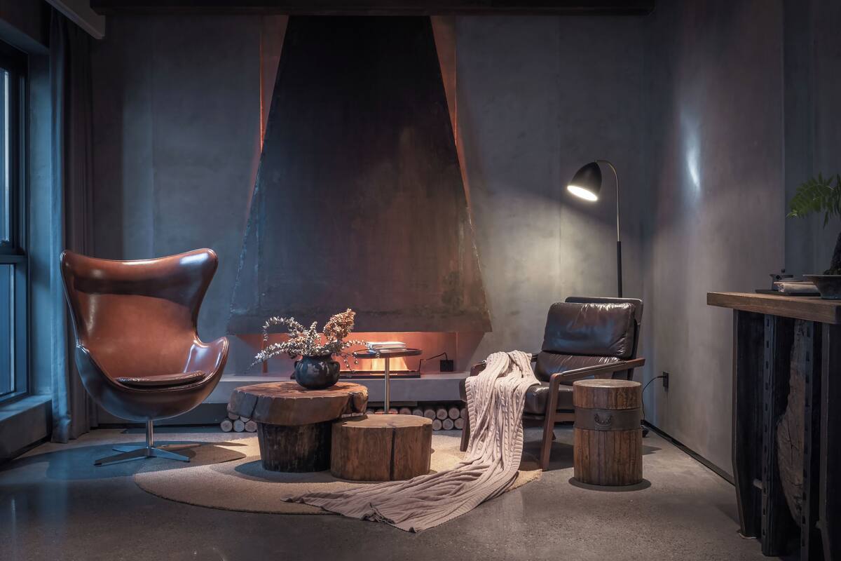 Ein gemütliches Zimmer mit Ledersessel, kleinem Tisch mit einer Vase, Decke und Stehlampe.