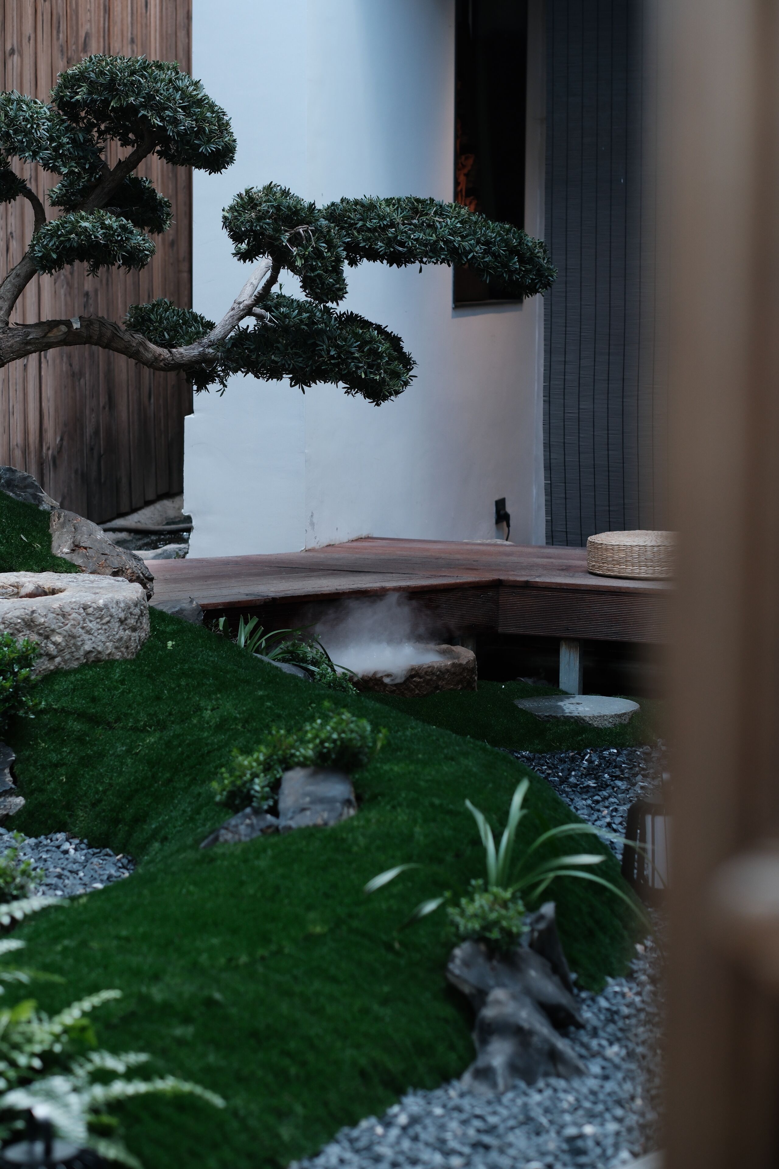 A Zen garden with a bonsai tree, rocks, and a wooden bench.