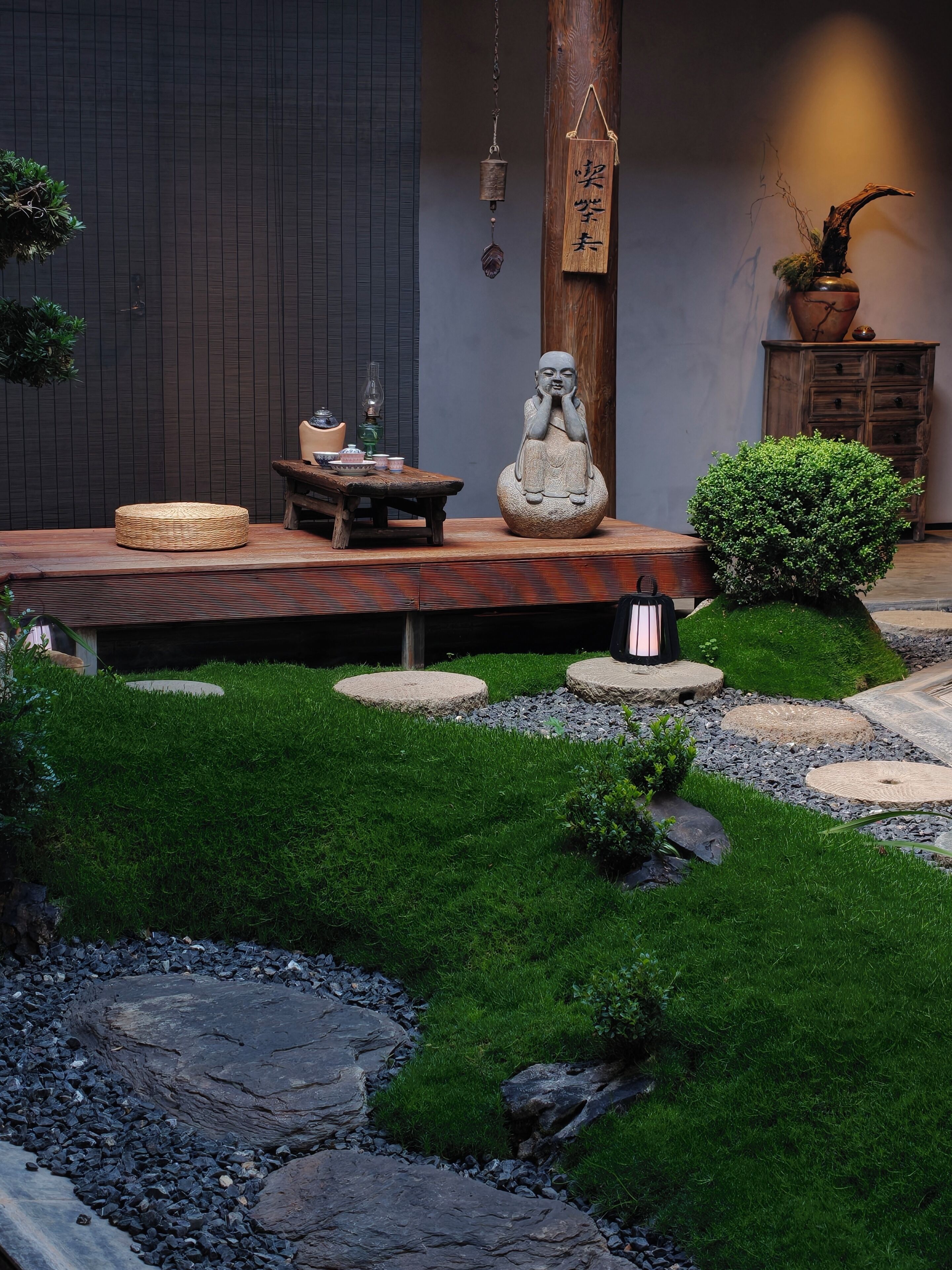 A Zen garden with a Buddha statue, a wooden table, and a traditional Japanese lantern.