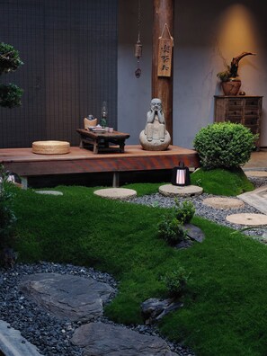 Ein Zen-Garten mit Buddha-Statue, einem Holztisch und einer traditionellen japanischen Laterne.