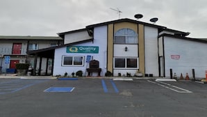A building with a 'Quality Inn' sign, a parking lot, and a gated entrance. - King Bed|Walkin|Victorville (Victorville CA)