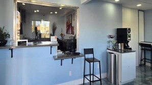 A modern interior with a bar area, a large mirror, and a coffee machine.