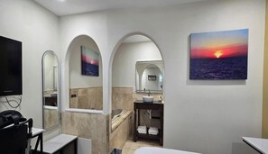 A modern bathroom with a bathtub, a sink, and a mirror. There are two arched doorways leading to other rooms.