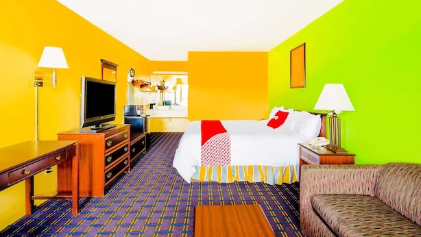Een hotelkamer met een bed, een televisie, een bureau en een bank.