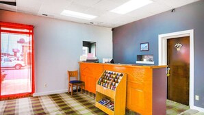 A reception area with a check-in counter, a chair, a bulletin board, and a door with a horse emblem.