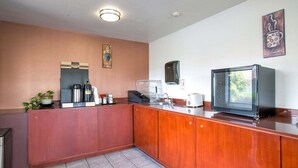 A compact kitchen with a coffee maker, toaster, and a microwave on the counter.