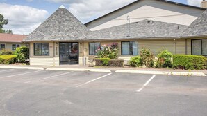 A single-story building with a gabled roof, a small attached office, and a parking lot.