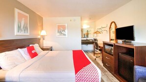 A hotel room with a bed, a desk, a television, and a mirror.